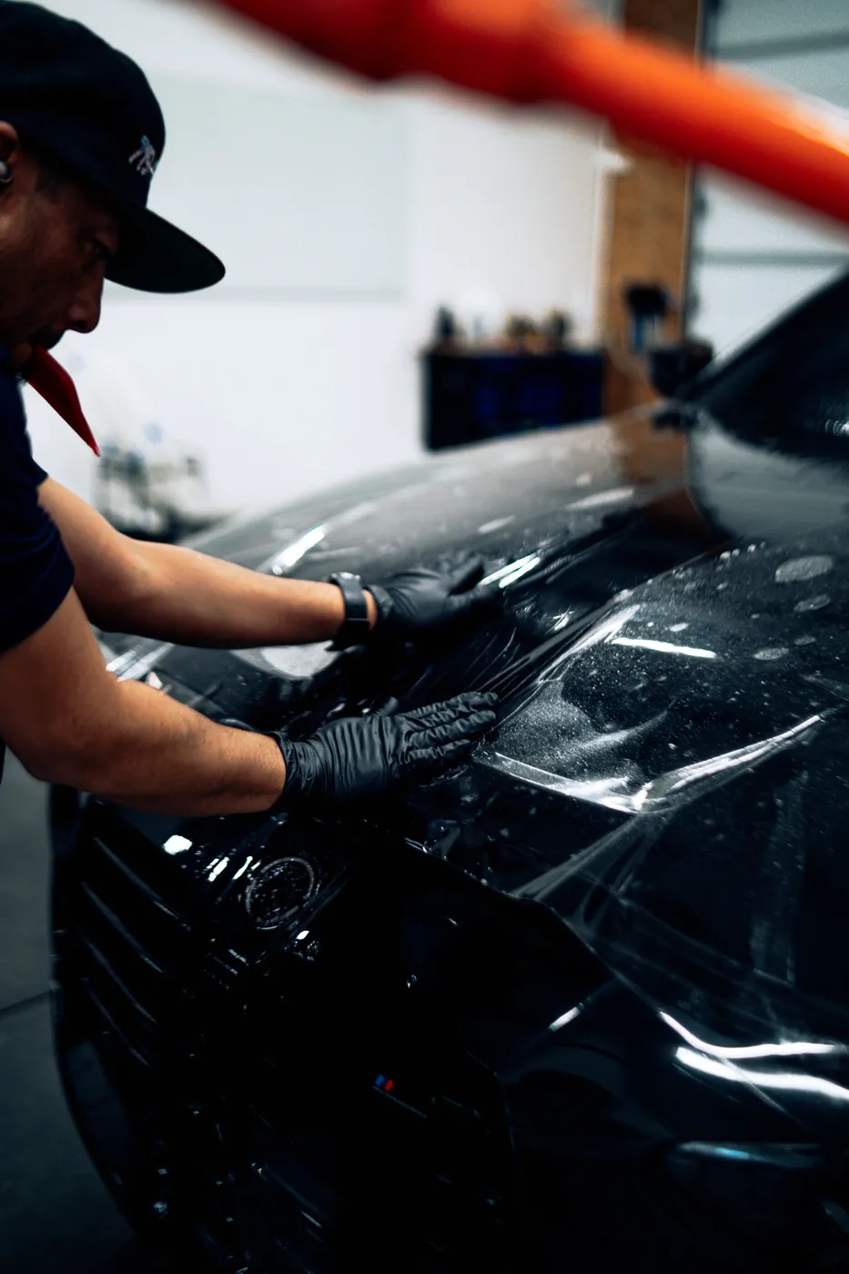 Installer working film onto a black vehicle